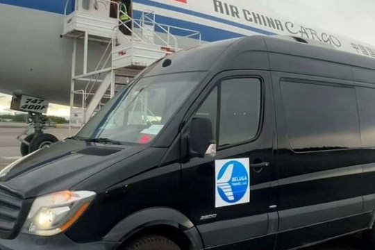 Black van parked in front of Air China Cargo plane on airport tarmac.
